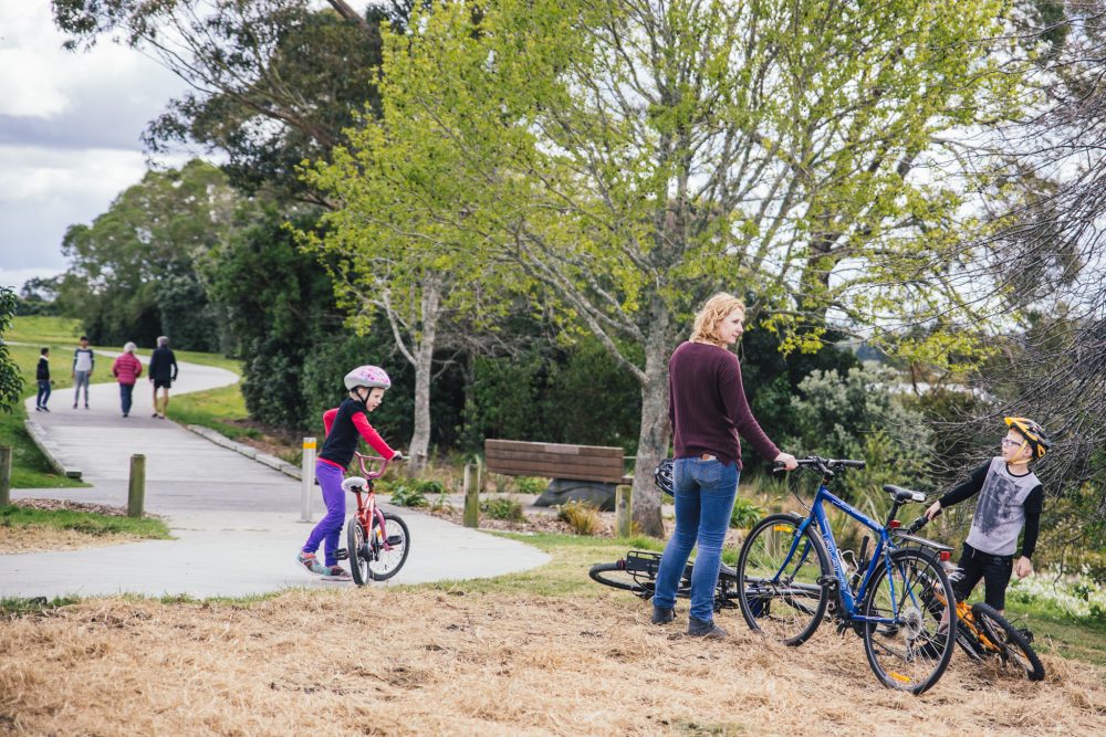 People walking and cycling along a riverside path.